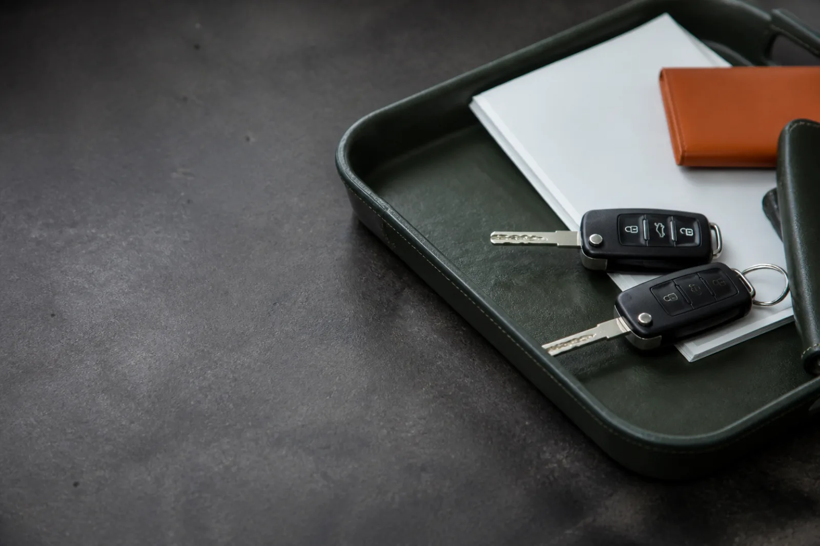 Automotive keys beside blank vehicle documents and a neutral service tray.