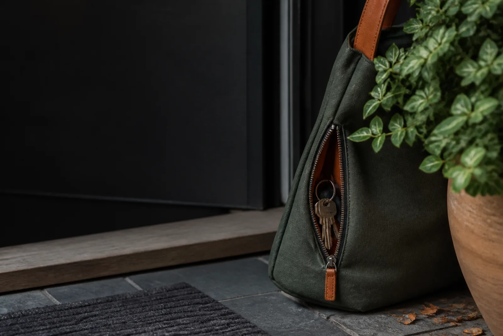 Keys secured in a zipped bag pocket beside a residential threshold.
