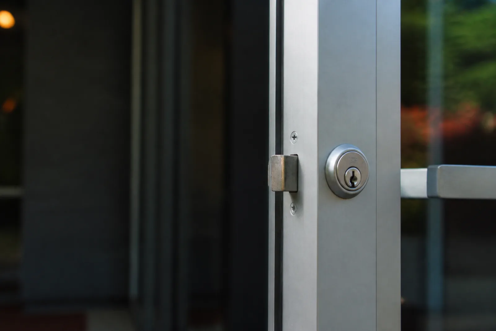 Commercial aluminum door cylinder, latch, and frame in close detail.