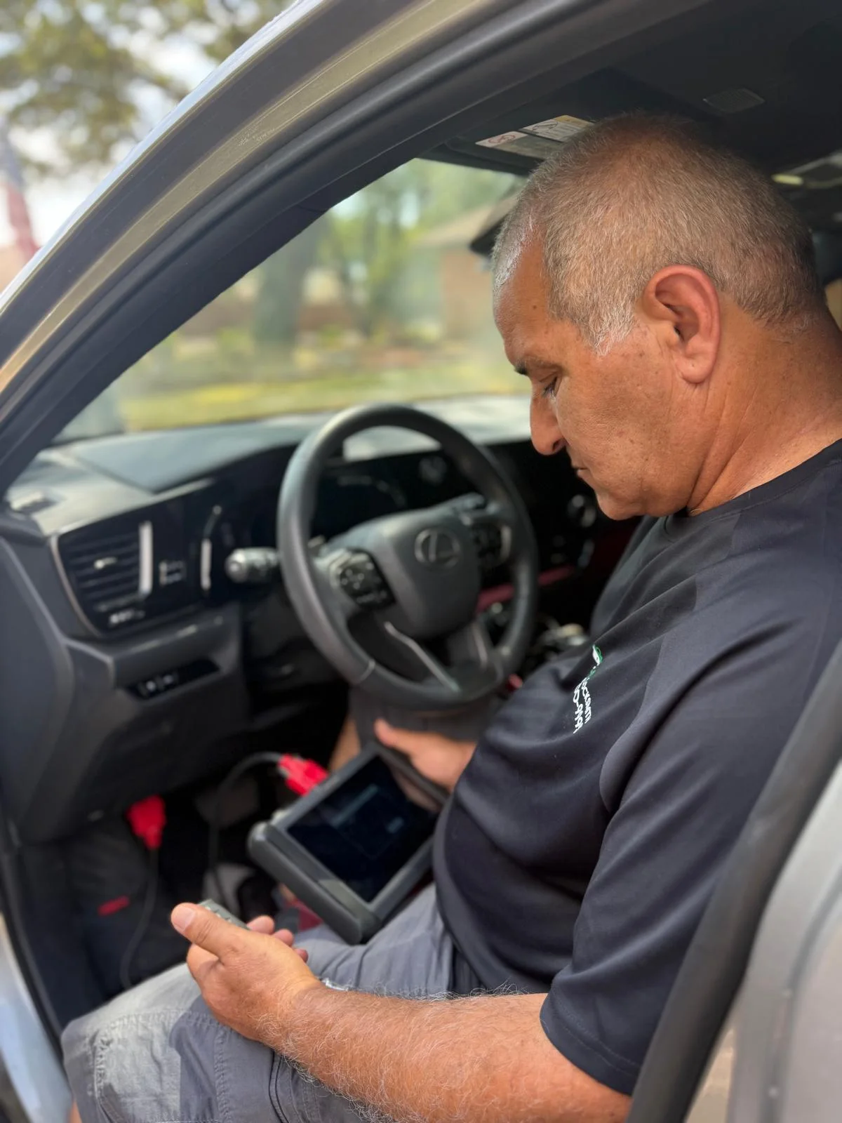 Hi-Q Locksmith owner Isaac programming a vehicle key with a diagnostic tablet in Fort Worth, Texas